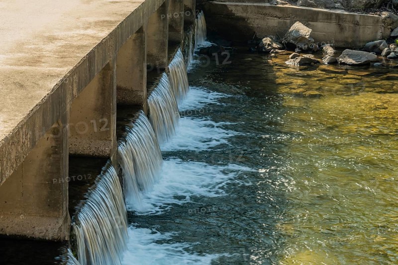 Water flowing smoothly over a concrete dam spillway, in South Korea