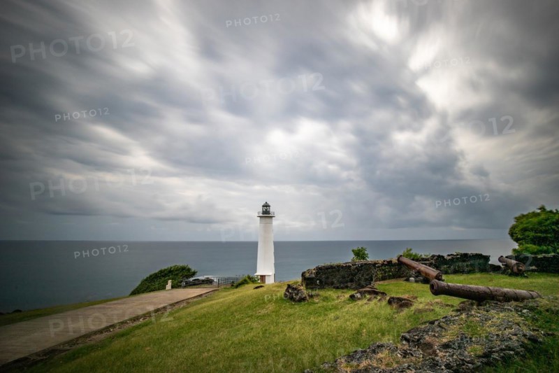 White lighthouse on a steep coast. Dramatic clouds with a view of the sea, pure Caribbean at Le Phare du Vieux-Fort, on Guadeloupe, French Antilles, France, Europe