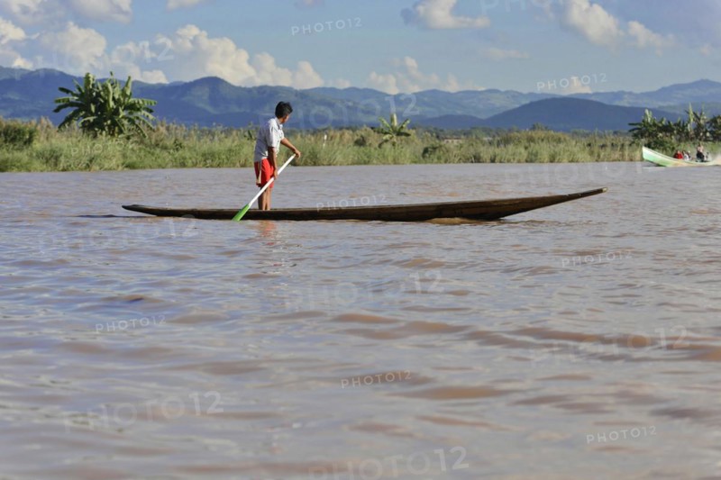 A child stands on a narrow boat on a quiet river, Inle Lake, Myanmar, Asia