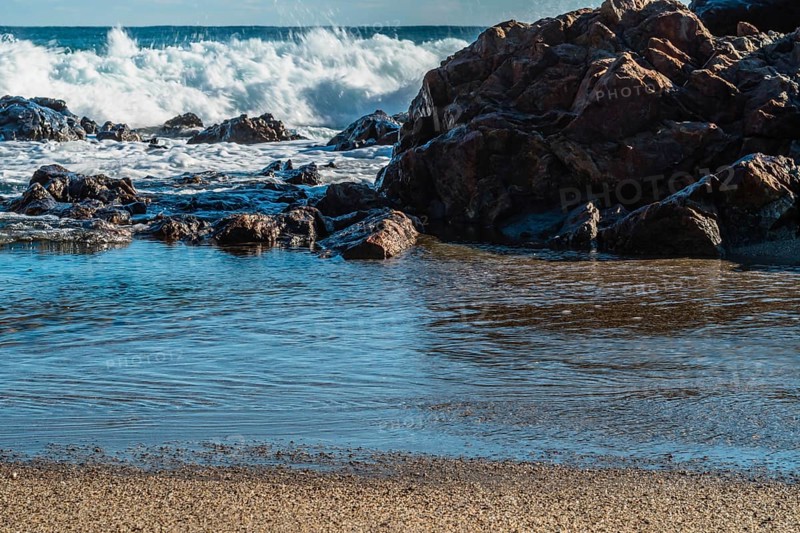 Crashing waves on rocky coastline with clear blue sky overhead, in South Korea