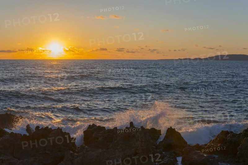 Sunset over the sea with waves breaking on rocks under a partly cloudy sky, Finikounda, Pylos-Nestor, Messinia, Peloponnese, Greece, Europe