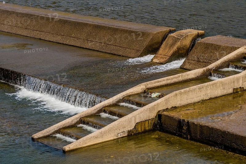 Concrete river dam with water overflowing on a sunny day, in South Korea