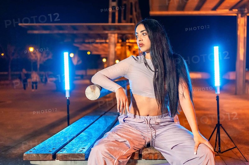 Portrait of a cool hip hop dancer sitting in an urban park at night
