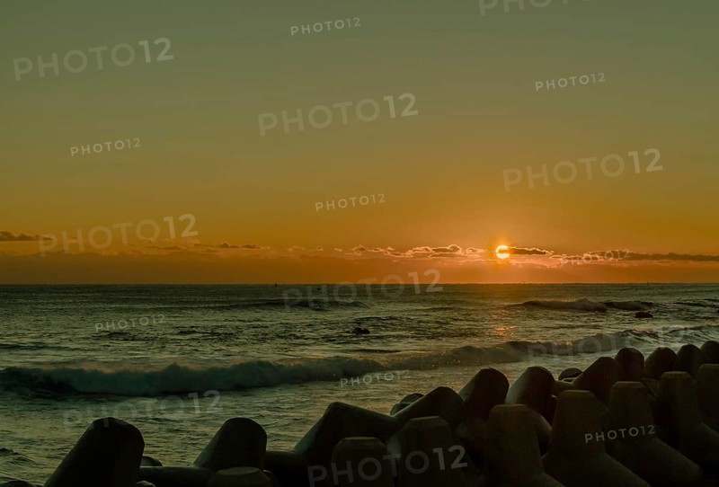 Warm sunrise over the ocean with waves crashing against tetrapods, in South Korea