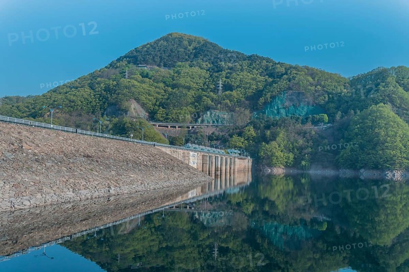 Beautiful lake area with dam and treeline reflected off the calm blue water at Daecheon Lake in South Korea
