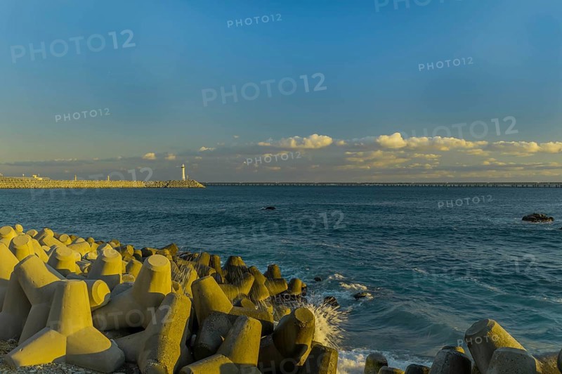 A lighthouse oversees the calm sea with tetrapods used for coastal protection at dusk, in South Korea