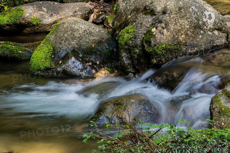 Small water fall cascading down rocks in the middle of a small mountain stream in Guam
