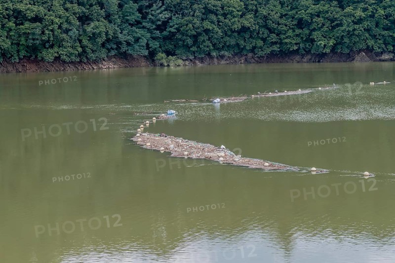 Island of trash and debris in reservoir being collected by net in Daejeon South Korea