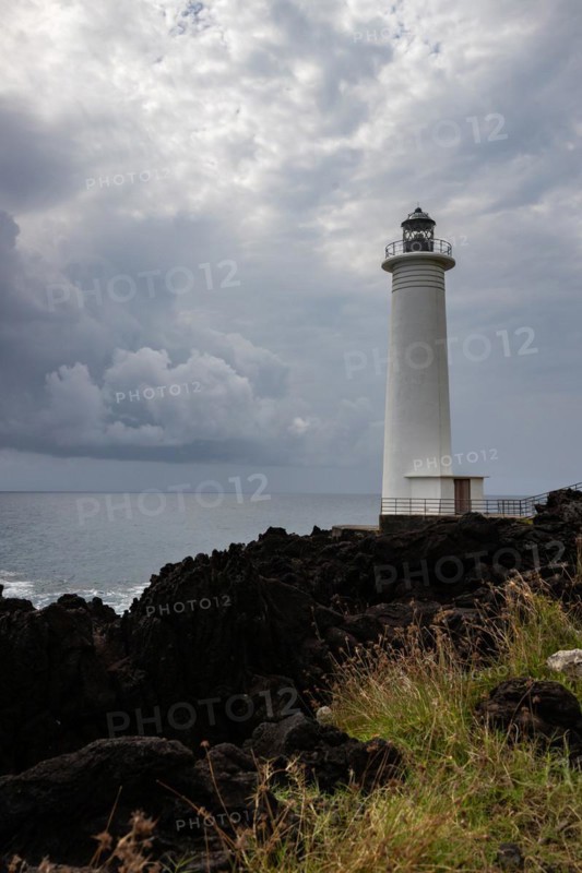 White lighthouse on a steep coast. Dramatic clouds with a view of the sea, pure Caribbean at Le Phare du Vieux-Fort, on Guadeloupe, French Antilles, France, Europe