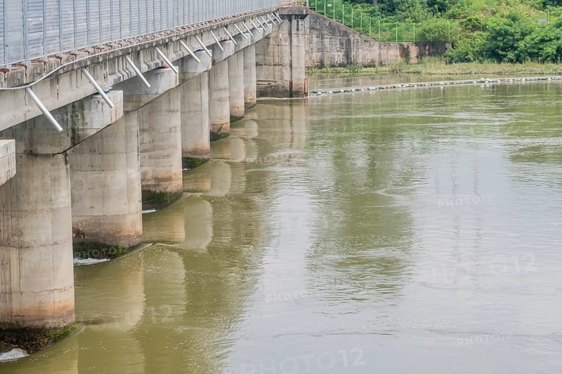 A sturdy concrete bridge spans across a wide river, reflected on the water's surface, in South Korea