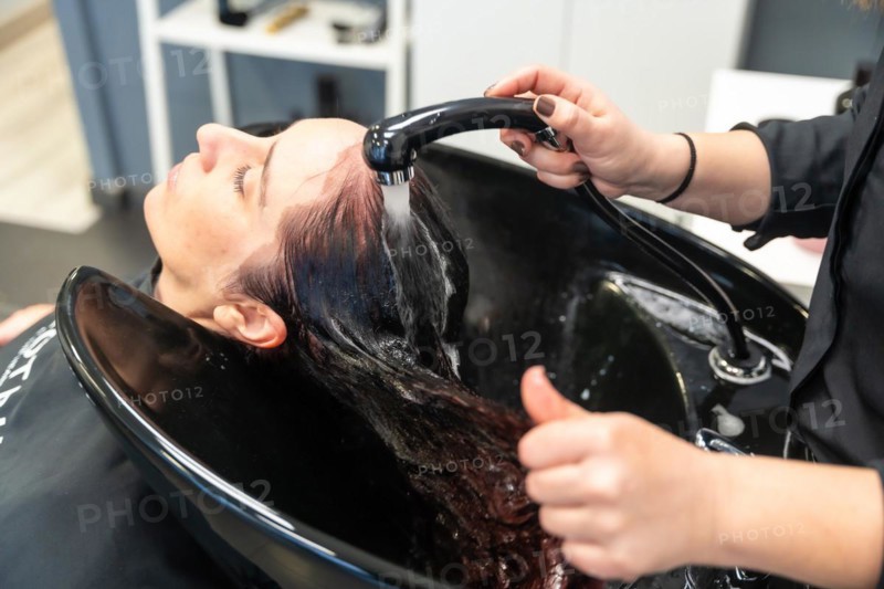Top view of the hands of a hairdresser washing the long hair of a client in a hair salon