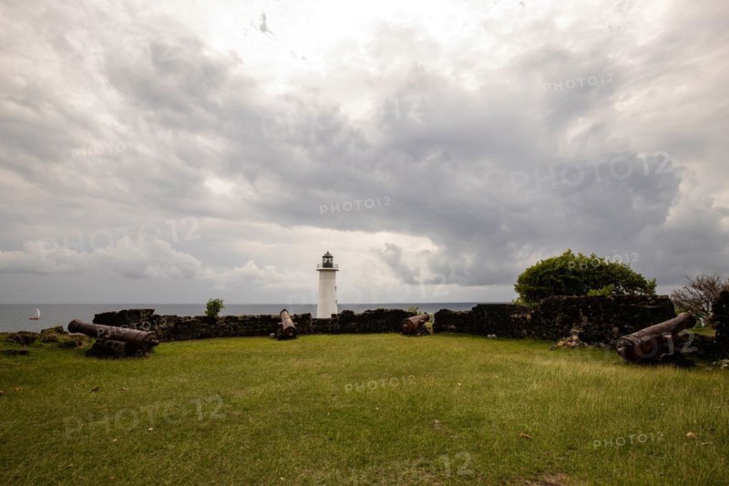 White lighthouse on a steep coast. Dramatic clouds with a view of the sea, pure Caribbean at Le Phare du Vieux-Fort, on Guadeloupe, French Antilles, France, Europe
