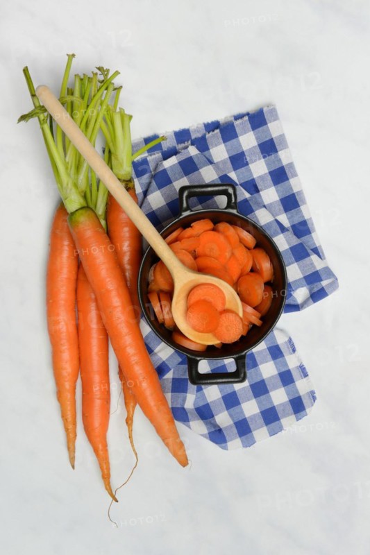 Carrot slices in pots and wooden spoon, carrot (Daucus carota)