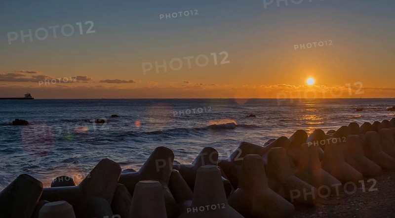 Tranquil sunset with orange sky over sea and tetrapods lined up on the coast, in South Korea
