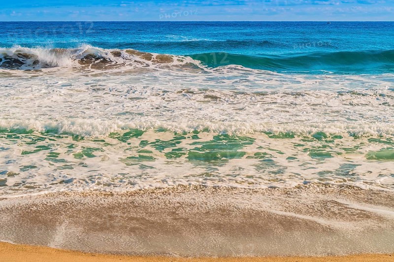 Seascape of whitecaps and waves as tide rolls in to shore on beautiful winter morning under partly cloudy sky, in South Korea