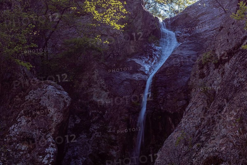 Water cascades down a rocky surface amid twilight hues, in South Korea
