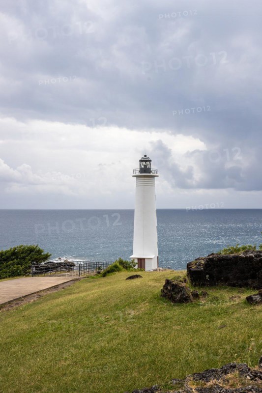 White lighthouse on a steep coast. Dramatic clouds with a view of the sea, pure Caribbean at Le Phare du Vieux-Fort, on Guadeloupe, French Antilles, France, Europe