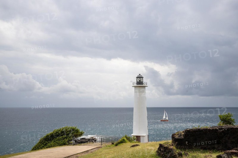 White lighthouse on a steep coast. Dramatic clouds with a view of the sea, pure Caribbean at Le Phare du Vieux-Fort, on Guadeloupe, French Antilles, France, Europe