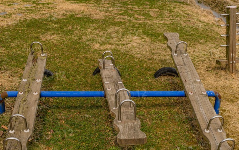 Wooden seesaw playground equipment on a well-maintained grassy field, in South Korea