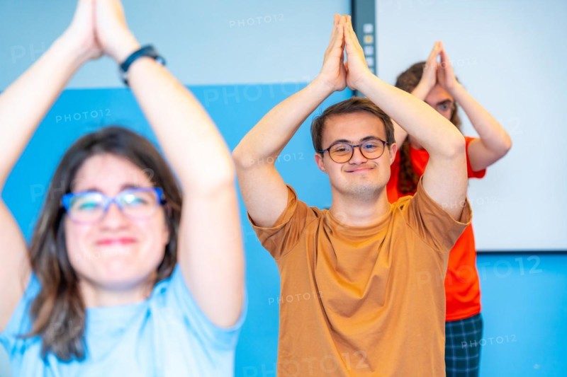 Happy group of disabled people raising arms practicing yoga in the gym