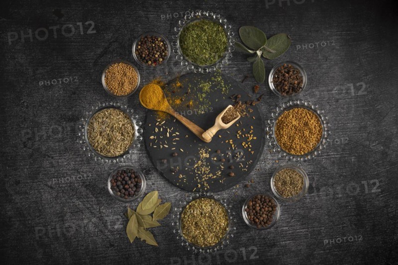 Spice clock, circular arrangement of various spices on a dark background