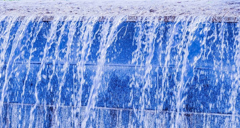 Blue-hued man-made waterfall streaming down a wall, in South Korea
