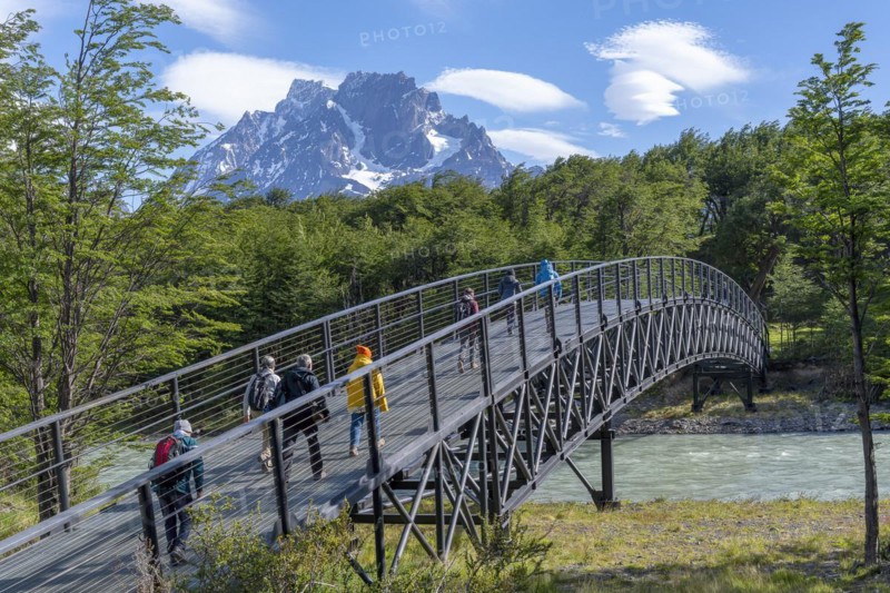 Tourists walk across a bridge over a tributary of Lago Grey, Torres del Paine National Park, Parque Nacional Torres del Paine, Cordillera del Paine, Towers of the Blue Sky, Region de Magallanes y de la Antartica Chilena, Ultima Esperanza Province, UNESCO Biosphere Reserve, Patagonia, End of the World, Chile, South America