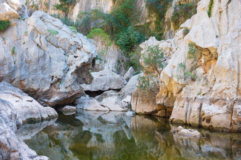 Torrent de Pareis, calm water surface in a riverbed of a mountain stream surrounded by impressive, almost white rock formations and sparse Mediterranean vegetation, reflection, mountains, Serra de Tramuntana, Majorca, Spain, Europe