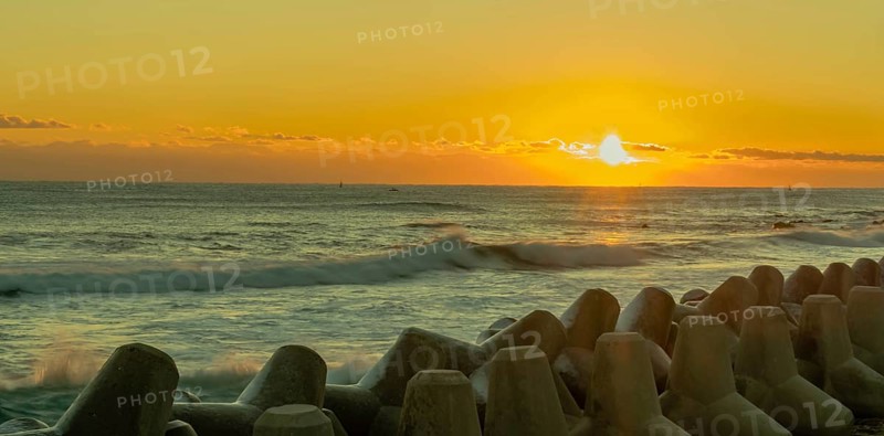 Beautiful sunset scene over the ocean with waves crashing against a breakwater, in South Korea