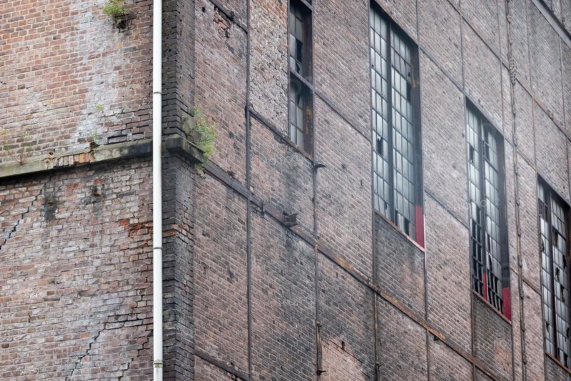 Old industrial building with weathered brick wall and rusty window frames