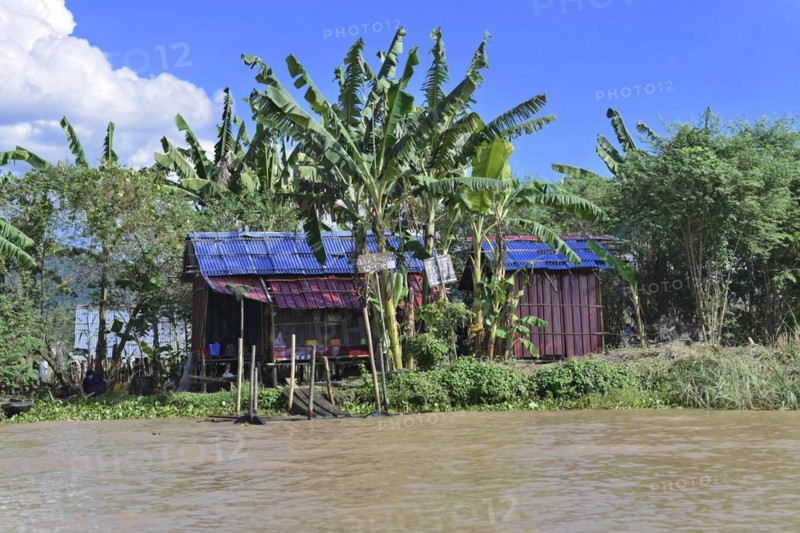Colourful wooden houses on a quiet riverbank surrounded by lush vegetation, Inle Lake, Myanmar, Asia