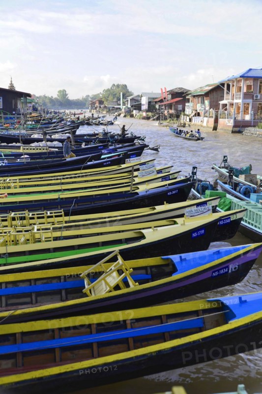 Row of colourful boats on a river bank with houses in the background, Pindaya, Inle Lake, Myanmar, Asia
