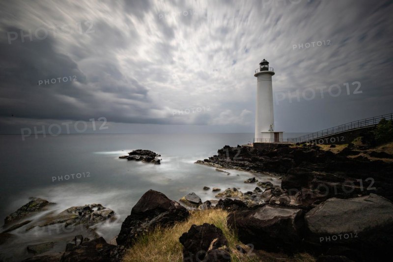 White lighthouse on a steep coast. Dramatic clouds with a view of the sea, pure Caribbean at Le Phare du Vieux-Fort, on Guadeloupe, French Antilles, France, Europe