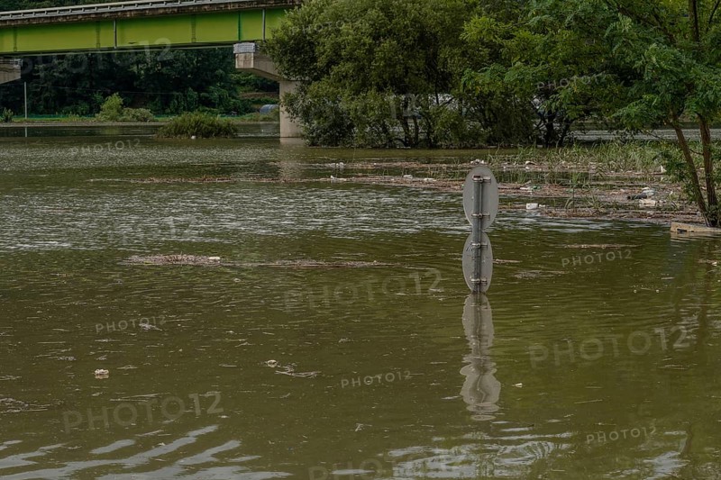 Round traffic signs and trees near bridge submerged in flooded river after torrential monsoon rains in Daejeon South Korea