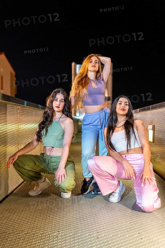 Vertical portrait of three beauty hip hop dancers posing together in the city at night