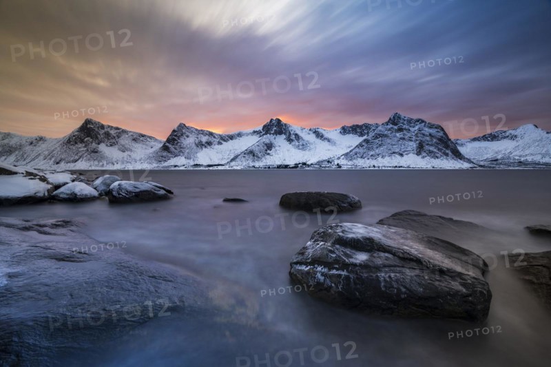 Rocky coast at the fjord with snow-covered mountains at sunset, Steinfjorden, Tungeneset, Husfjellet, Senja Island, Norway, Europe