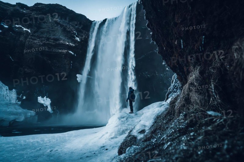 Silhouette of woman in winter in Iceland under Skogafoss waterfall