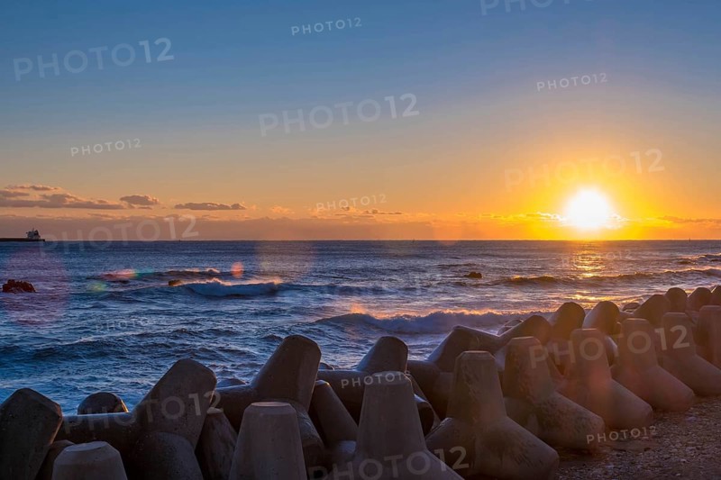 Amber sky during sunrise over sea with tetrapods and soft waves hitting the shore, in South Korea
