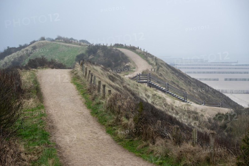 A path leads through dunes to the beach, next to it a wooden staircase