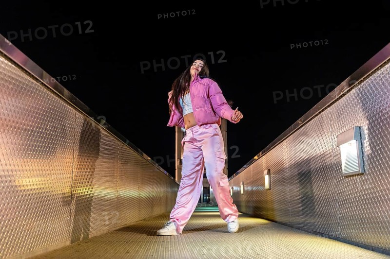 Low angle view photo of a young artist dancing hip hop on a bridge at night