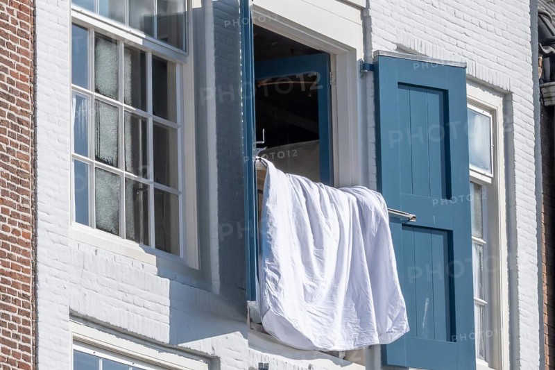 Close-up of an open window with blue shutters and a white shirt, Middelburg, Zeeland, Netherlands