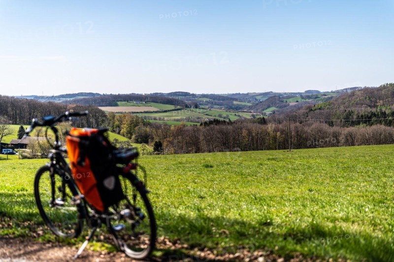 Packed bicycle in front of picturesque spring landscape with green meadows and blue sky, Deilbachtal, Langenberg, Velbert, Mettmann, Bergisches Land, North Rhine-Westphalia