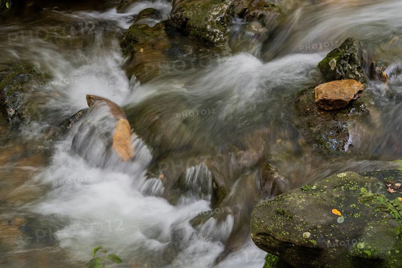 Small water fall cascading down rocks in the middle of a small mountain stream in Guam