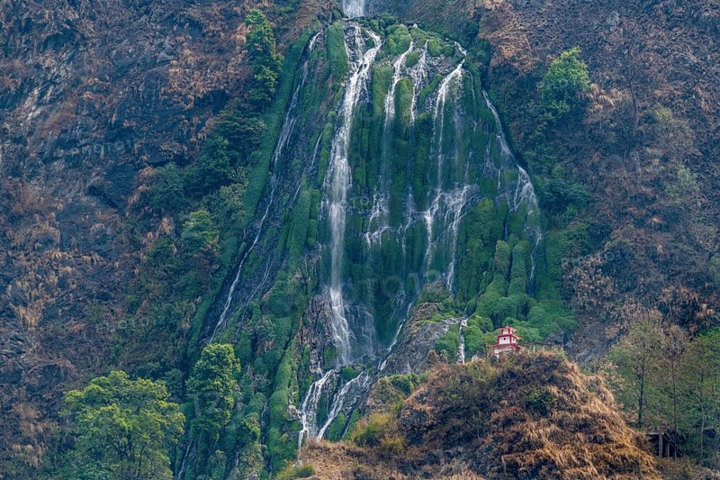 Little stupa undeaneath a huge waterfall, along the highway to Jomsom, Nepal, Asia