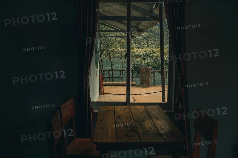 A rustic table by a window opening to a serene lake surrounded by forested hills