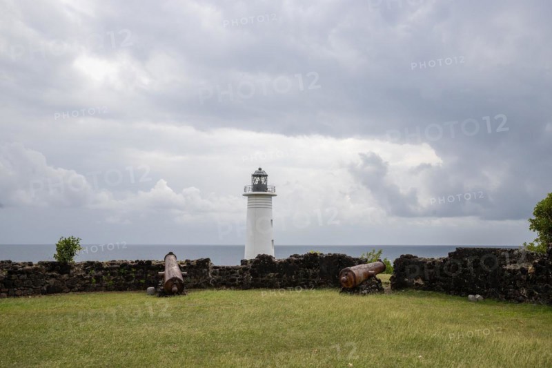 White lighthouse on a steep coast. Dramatic clouds with a view of the sea, pure Caribbean at Le Phare du Vieux-Fort, on Guadeloupe, French Antilles, France, Europe