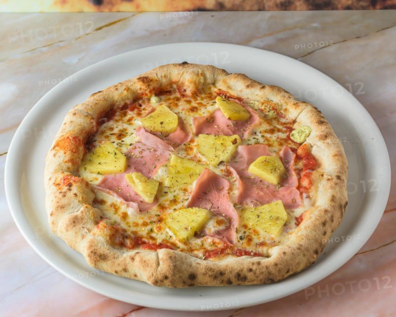 Tropical Hawaiian pizza with pineapple slices and ham on a baked dough base served whole with copyspace, pizza