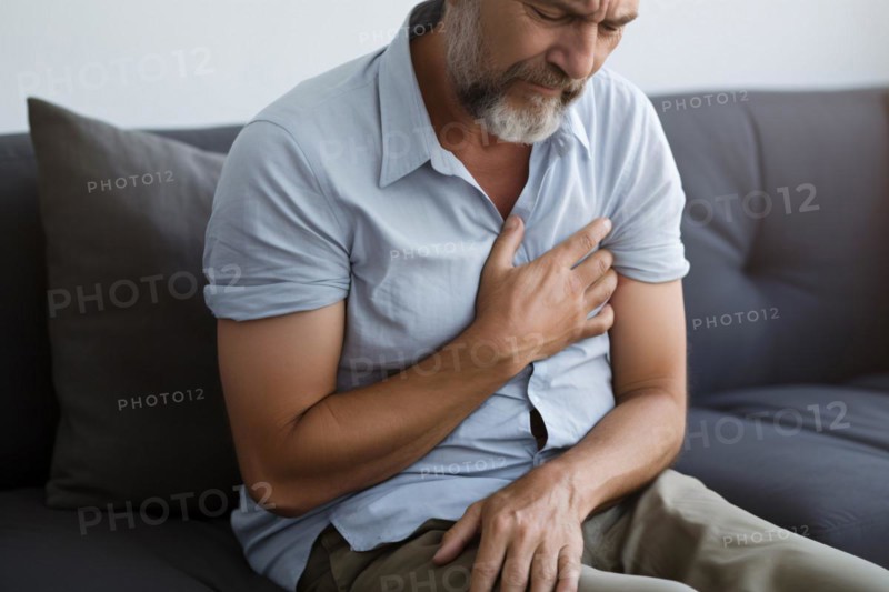 Middle aged man holding hand to chest in pain. Concept for hear attack or ache. KI generiert, generiert AI generated
