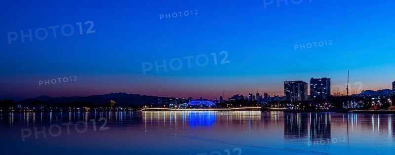 Tranquil city waterfront under the hues of dusk, with lights reflecting on water, in South Korea