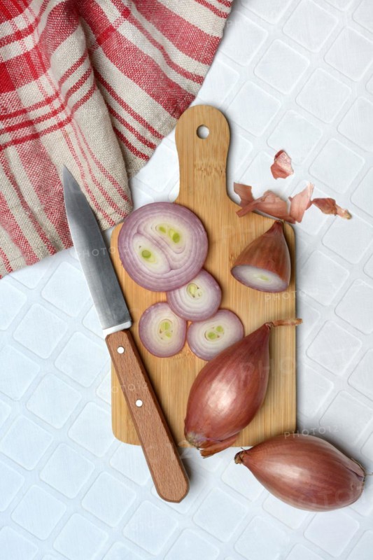 Shallots on wooden board with knife, Allium cepa